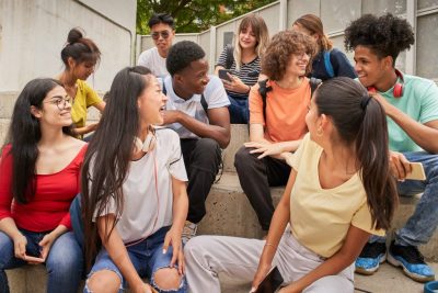Diverse group of high school students sitting on stairs, smiling and talking