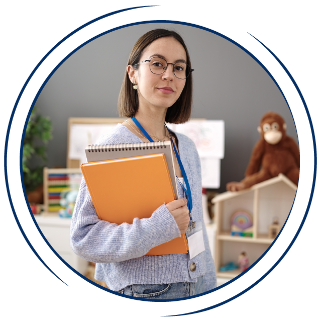 A young white woman with short brown hair and glasses stands in a classroom. She wears a blue lanyard around her neck and holds notebooks and files, all in a circular frame. A Special Education Teacher