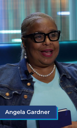 A middle aged African American woman sits in the lobby of a hotel. She wears black glasses, a blue tee shirt, a jean jacket, and a pearl necklace. She holds a blue planner, and smiles while speaking. In the bottom left corner is a blue box with white text in it that reads "Angela Gardner".
