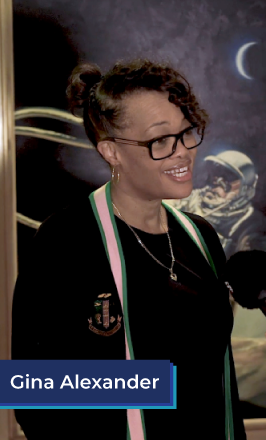 A middle aged black woman stands in front of a poster if an astronaut. She wears her hair in a bun and has glasses. She is wearing a black shirt, gold necklace, and black, pink, and green sweater. She is smiling. In the bottom left corner is a blue box with white text in it that reads "Gina Alexander". Michigan Special Education Teacher