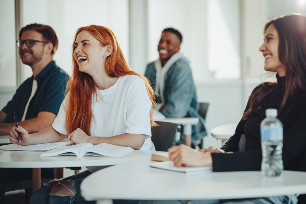 A group of high school students smiling and engaging in a classroom, participating in a discussion on college preparation.