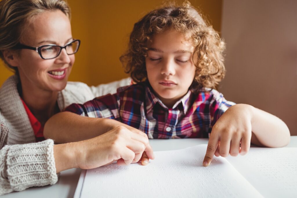 Boy using braille to read with the help of a school orientation and mobility specialist.