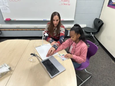 Student using assistive technology with teacher support in a classroom